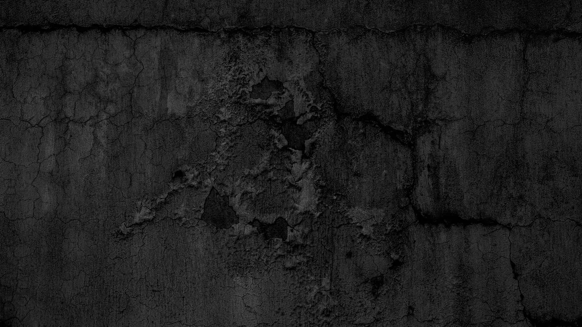 Muro de hormigón oscuro y agrietado con la capa superficial desconchada, dejando ver el daño que hay debajo.